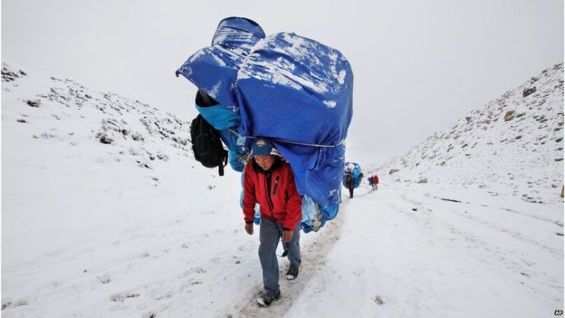 Ένας αχθοφόρος περπατά με ένα ογκώδες φορτίο προς το στρατόπεδο βάσεων Everest